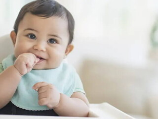 Bebé de 9 meses sentado sonriendo.