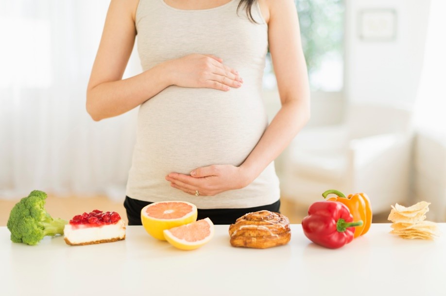 Mujer tocando su vientre, con alimentos saludables.