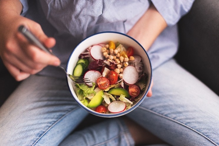 Mujer comiendo vegetales ricos en ácido fólico 