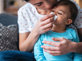Mujer descongestionando la nariz de un bebé.