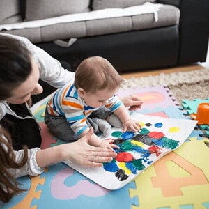 Actividades y juegos divertidos para estimular el desarrollo cognitivo Una mujer y un bebé jugando en una alfombra colorida.