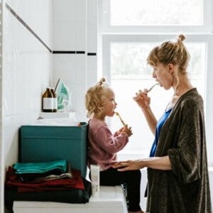 Conoce cuáles son los hábitos de higiene para niños. Mamá y niña en el baño cepillándose en el baño.