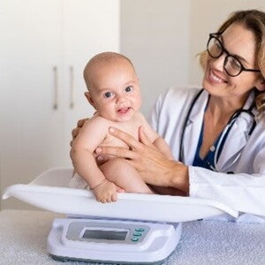 La tabla de peso en niños es un herramienta muy útil. Doctora pesando al bebé.