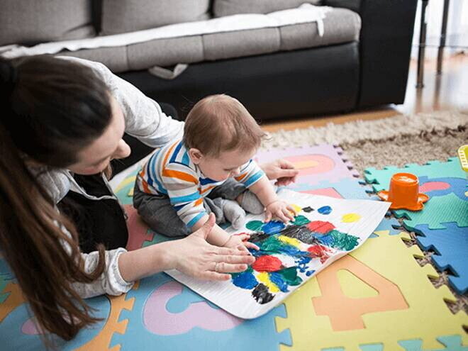 Actividades y juegos divertidos para estimular el desarrollo cognitivo Una mujer y un bebé jugando en una alfombra colorida.
