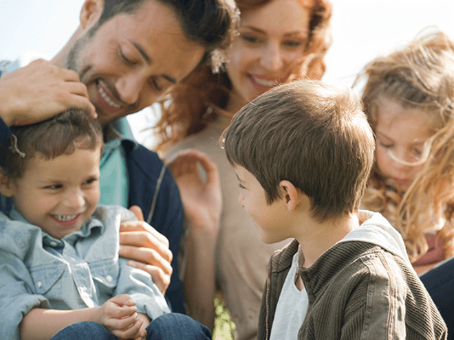 Beneficios y desafíos de las familias ensambladas Una linda familia disfrutando juntos en el césped con un niño