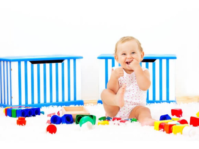 Es importante saber a los cuántos meses se sienta un bebé y acompañar este proceso Bebé sonriendo sentado al lado de sus juguetes