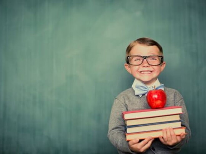 Conoce qué son las estrategias de aprendizaje. Niño sonriendo con libros en la mano.