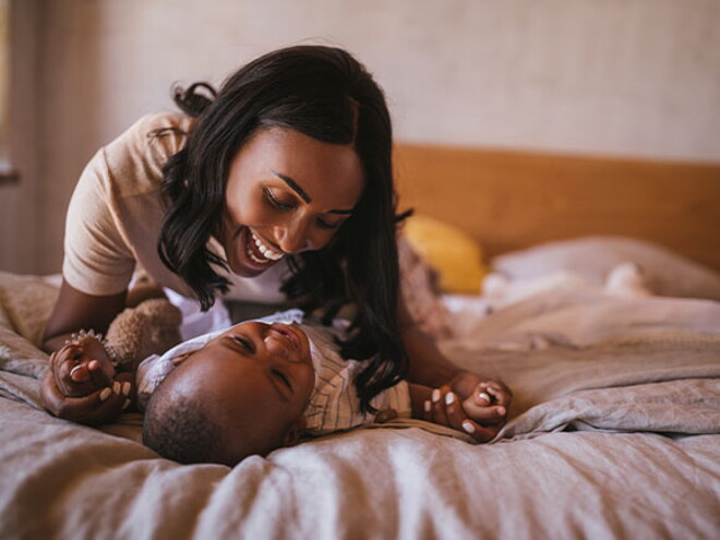 La mamá y el bebé haciendo ejercicios en la cama La mamá y el bebé haciendo ejercicios en la cama