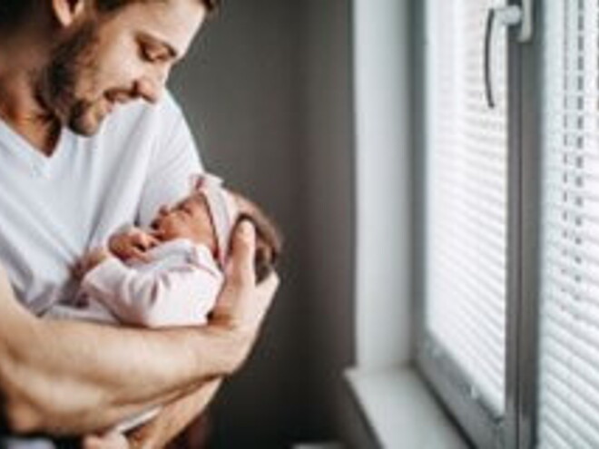 Papá alzando su bebé y revisando los granitos de su cara