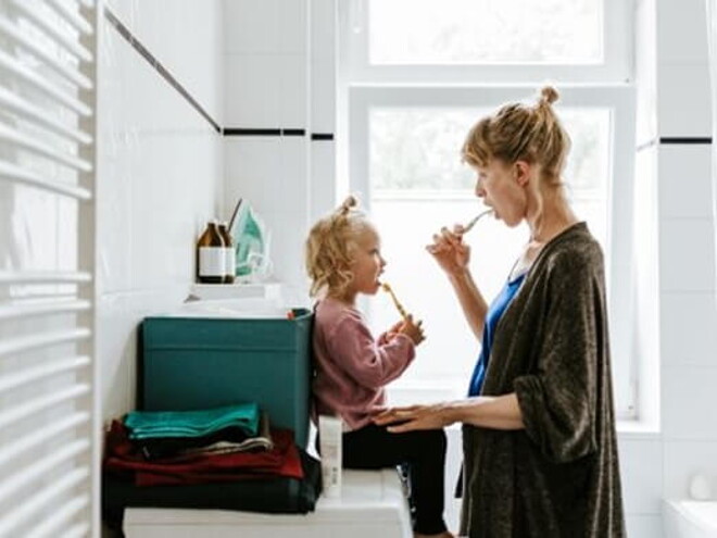 Conoce cuáles son los hábitos de higiene para niños. Mamá y niña en el baño cepillándose en el baño.