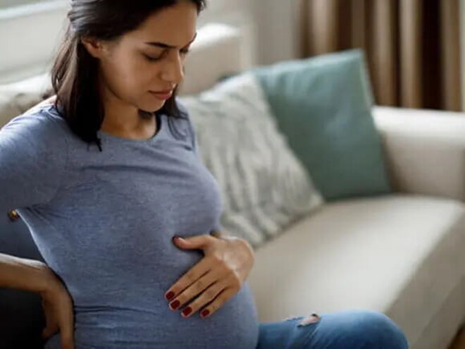 Mamá tocando el vientre y la espalda sintiendo molestia.