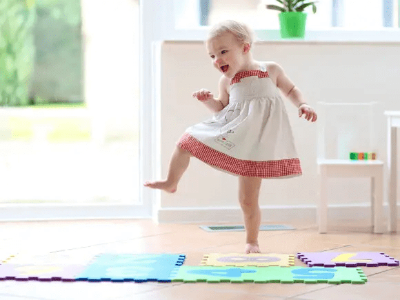 niña bailando sobre tapetes de goma para jugar