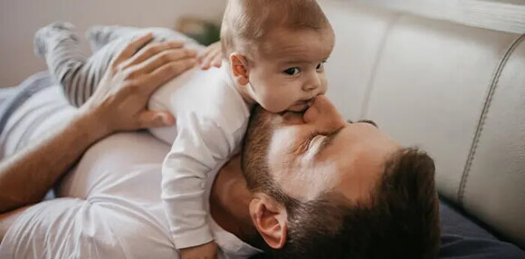 Los juegos son fundamentales para los bebés de cuatro meses. Papá cargando a su bebé de cuatro meses.