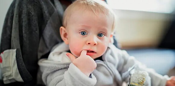 Algunos bebés de 12 meses comienzan a nacerle los dientes. Bebé de 12 meses con el dedo en la boca
