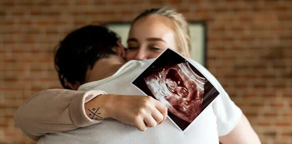 Pareja abrazados celebrando que tendrán un bebé arcoíris