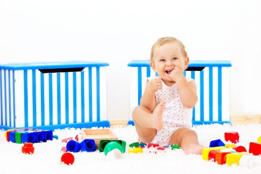Bebé de 9 meses sentada jugando en su lugar seguro