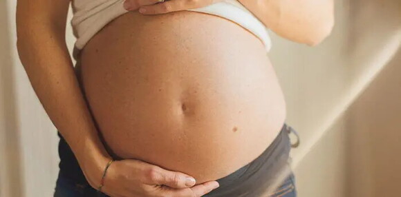 Conoce cuáles son las causas de la eclampsia. Mamá tocando el vientre.