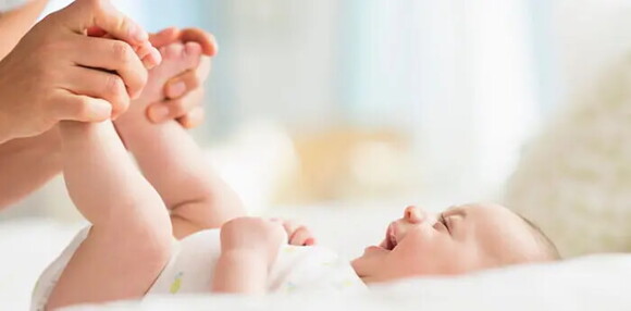 La coordinación visual hace parte del desarrollo de un bebé de tres meses. Bebé de tres meses jugando con un adulto.