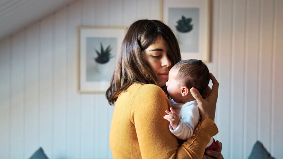 El vínculo con los padres hace parte del desarrollo emocional del bebé de un mes. Mamá cargando a su bebé de un mes.
