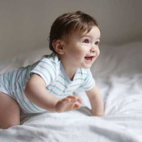 El gateo es fundamental en el desarrollo psicomotor. Niño sonriendo y gateando como parte del desarrollo psicomotor.
