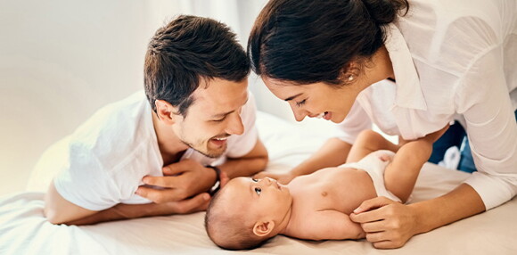 Papá y mamá felices luego de descongestionar la nariz del bebé.