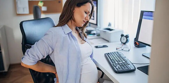 Identifica cuál es la diferencia entre preeclampsia y eclampsia. Mujer embarazada sentada sintiendo molestias.