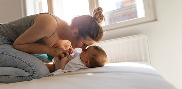 La mamá está con su bebé en la cama, listas para hacer ejercicios La mamá está con su bebé en la cama, listas para hacer ejercicios