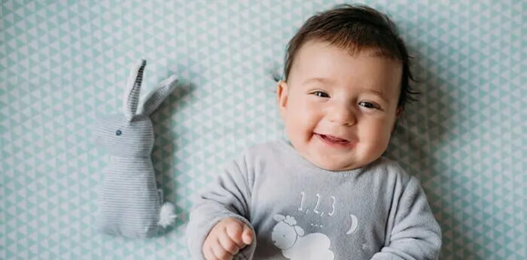 Los bebés de cuatro meses tienen mayor control de su cabeza y extremidades. Bebé de cuatro meses sonriendo.