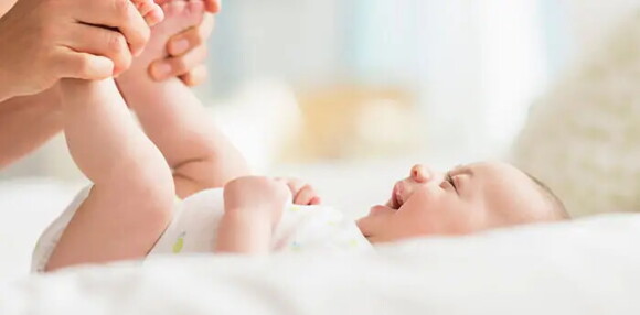 Un bebé de dos meses desarrolla habilidades motoras finas y gruesas. Bebé de dos meses sonriendo con las piernas levantadas.