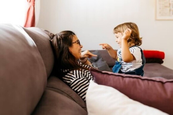 Realiza juegos y explícale por qué es importante los hábitos de higiene. Mamá y niña riendo y hablando de los hábitos de higiene.