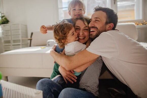 Papá y mamá abrazando a sus hijos.