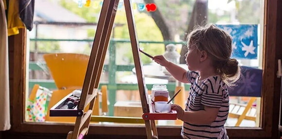 Identificar los estilos de aprendizaje te permite conocer más a tus hijos. Niña pintando con pinturas como parte de su aprendizaje.