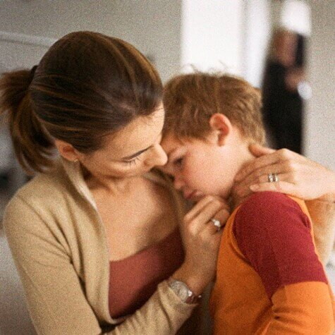 Mamá consolando a su hijo que está triste.