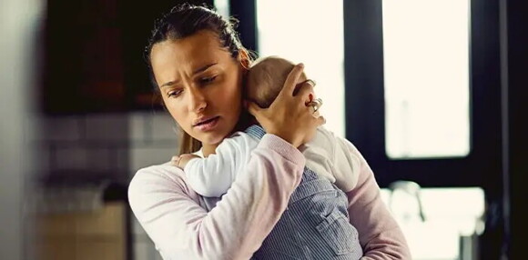 Mamá primeriza cargando a su bebé llorando.