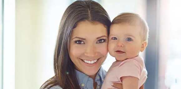 Mantener limpio el coche para bebés es importante para prevenir enfermedades. Mamá alzando a su bebé sonriente.